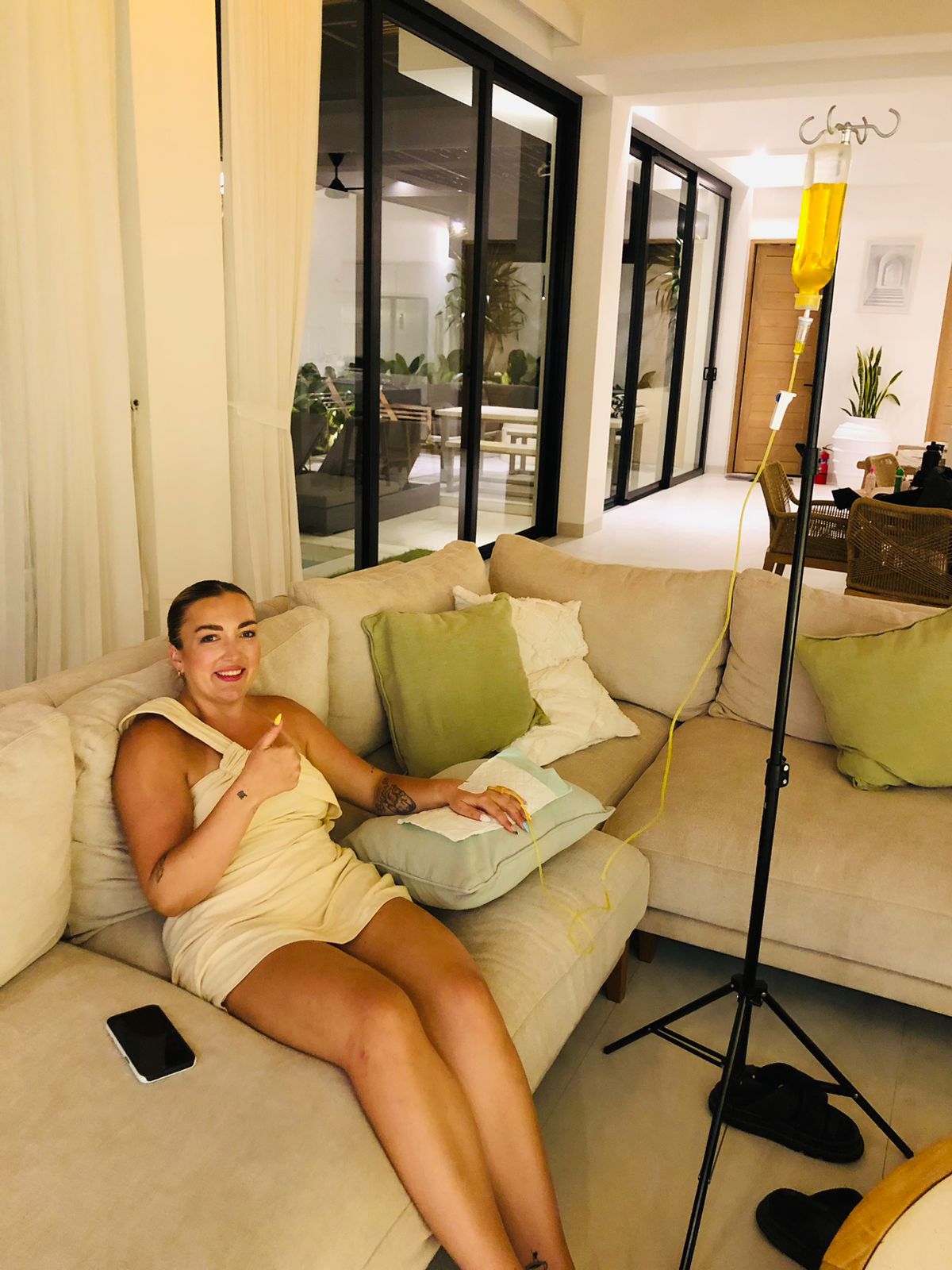 Woman relaxing on a sofa receiving a mobile IV drip treatment in a Bali villa.