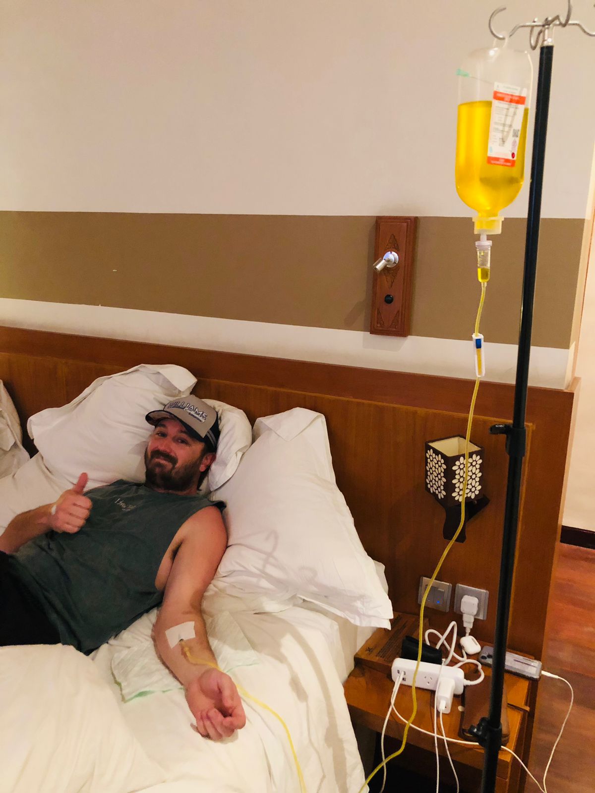 Man receiving a mobile IV drip hydration treatment while relaxing in a bed.