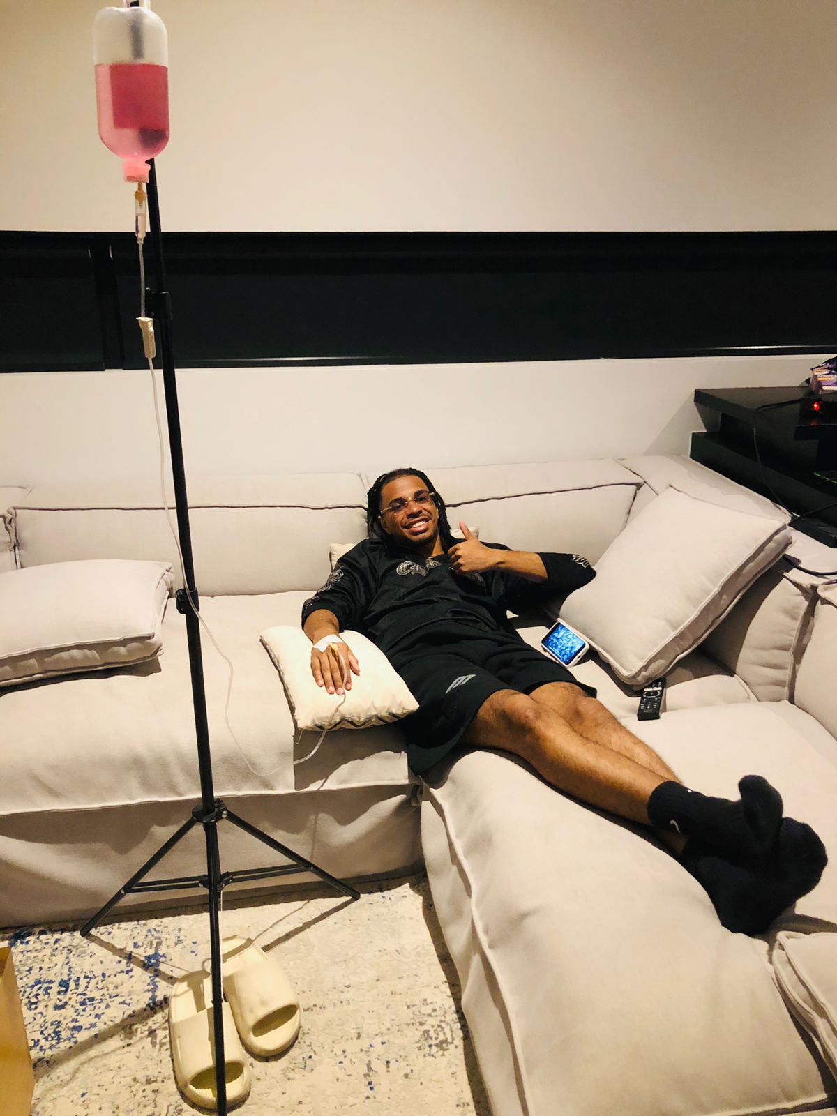 A man relaxing on a sofa while receiving a mobile IV drip therapy session.