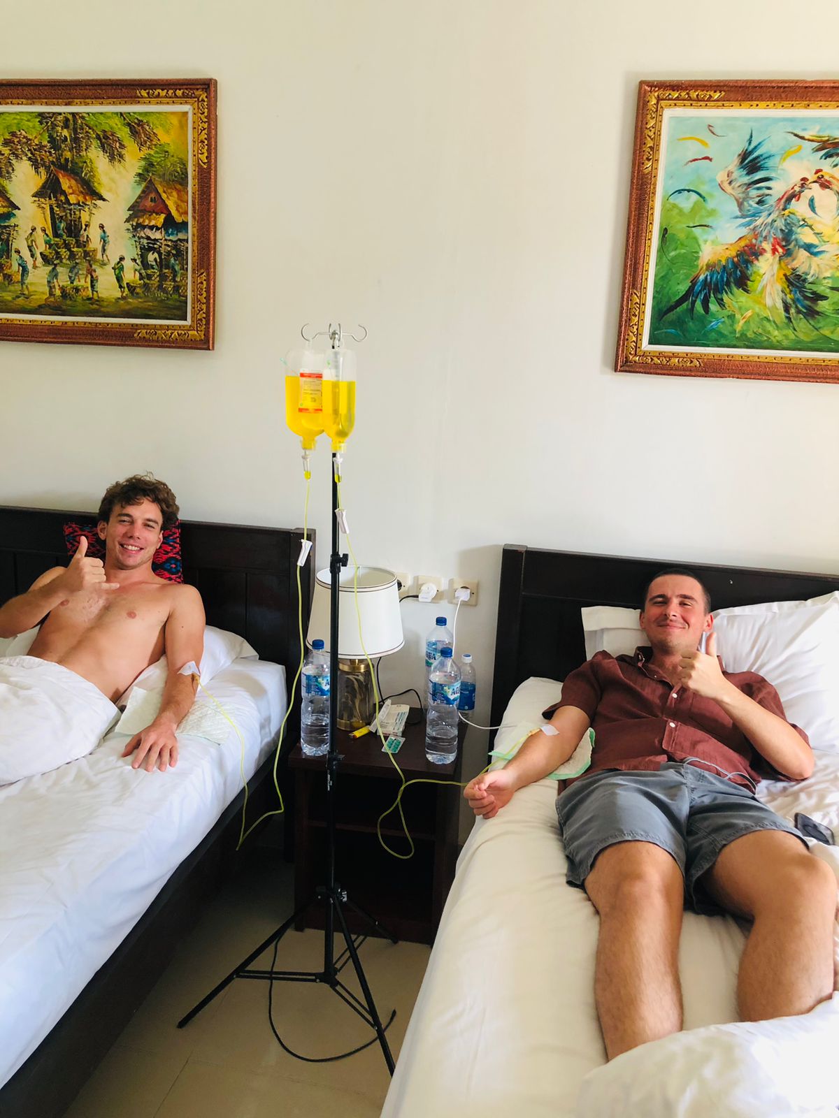 Two men receiving mobile IV drip hydration treatments in a Bali villa bedroom.